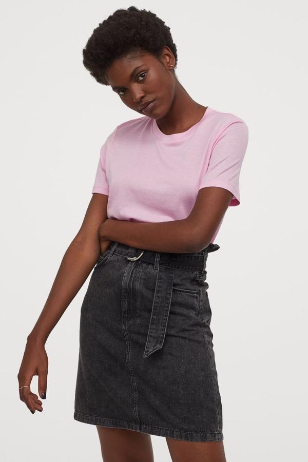 En denim de algodón lavado suave, esta falda mini de H&M de talle alto y cintura paper bag viene con cierre de cremallera con botones de metal y cintura extraíble a tono. De 24,99 euros ha pasado a costar 14,99 euros. Está disponible en las tallas 32, 34, 36 y 46, aunque la última se está agotando.