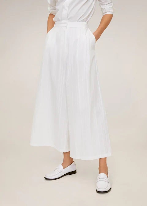Pantalón blanco de corte palazzo con estampado de rayas y tejido de algodón y lino. En Mango por 29,99 euros. Antes: 39,99 euros.