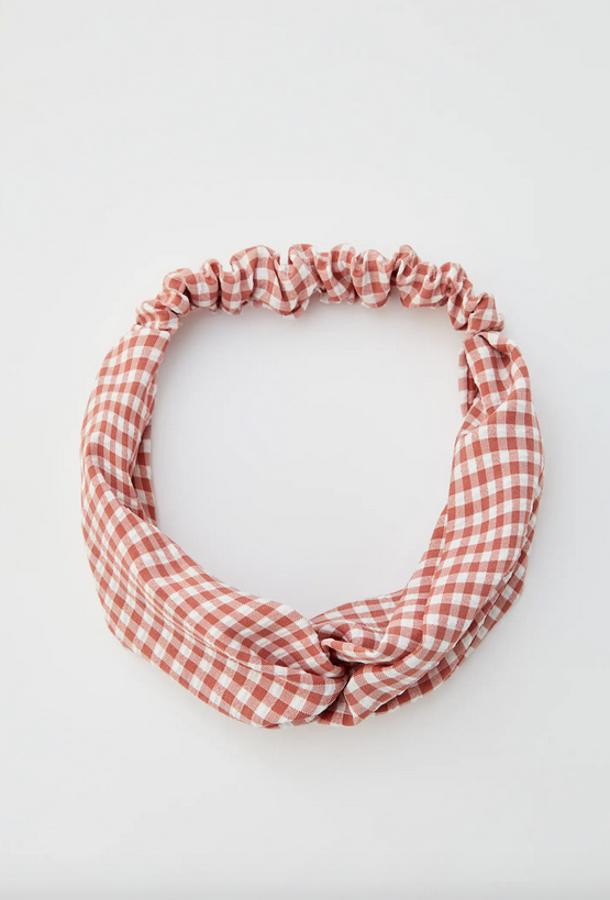 Print de cuadro vichy en color rosa para esta cinta de pelo con nudo y elástico de Pul&Bear que tiene un precio de 4,99 euros.