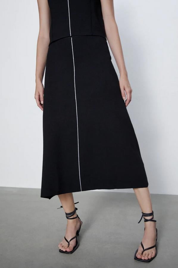 Con una original línea a contraste en color blanco, esta falda negra de Zara con bajo acabado en línea evasé es de tiro alto y tiene la cintura elástica. De 25,95 euros ha pasado a costar 9,99 euros y está disponible en las tallas S y M.