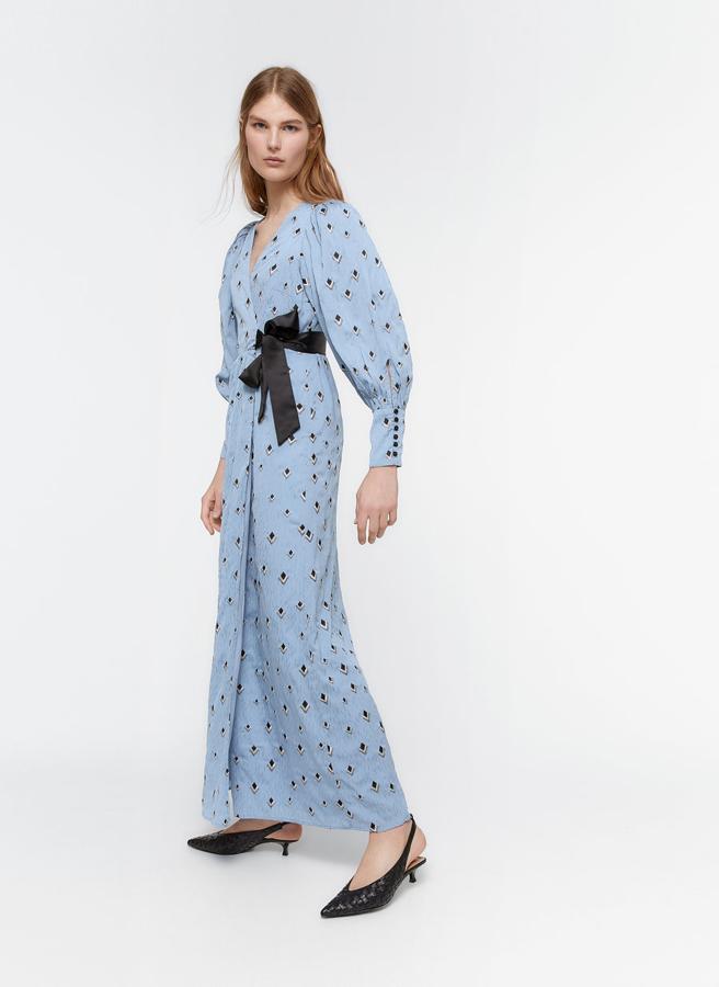 Con estampado a contraste en azul marino, este vestido de diseño de manga semi abullonada y detalle de puños con botones forrados en azul celeste tiene un lazo cruzado a contraste como cierre. Disponible entre las tallas XS y L, costaba 179 euros y ahora podemos comprarlo por 99,95 euros.