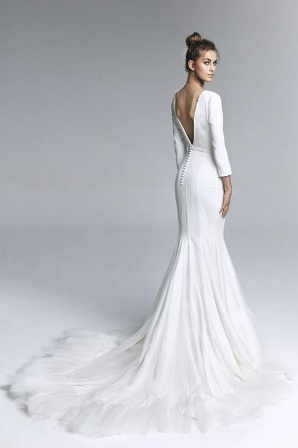 Vestido de novia con cuello barco y manga francesa, con cuerpo de crepe con bordado de perlas y falda de vuelo realizada en godet de crepe y tul seda. Rebajado de 2.390 a 956 euros.