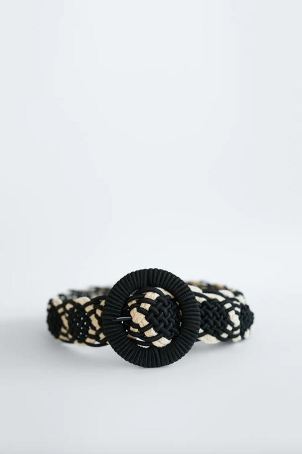 Uno de nuestros favoritos es este cinturón combinado de Zara en color natural y negro con diseño trenzado y hebilla forrada del mismo tejido en formato redondo. Cuesta 19,95 euros y está disponible en las tallas 80 y 90.
