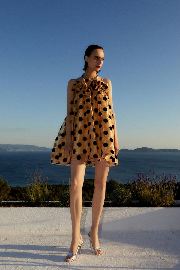 Vestido de vuelo mini, en tejido brillante, y lunares marcados en negro sobre la tela, de la nueva colección de Sfera (49,99 euros).