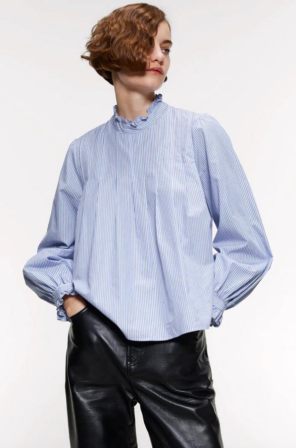 En Zara hemos encontrado esta blusa de cuello subido y manga larga, ambos acabados en volante. Con detalle de frunces en la pechera, está rebajada y de 29,95 euros ha pasado a costar 9,99 euros. Está disponible entre las tallas XS y XL.