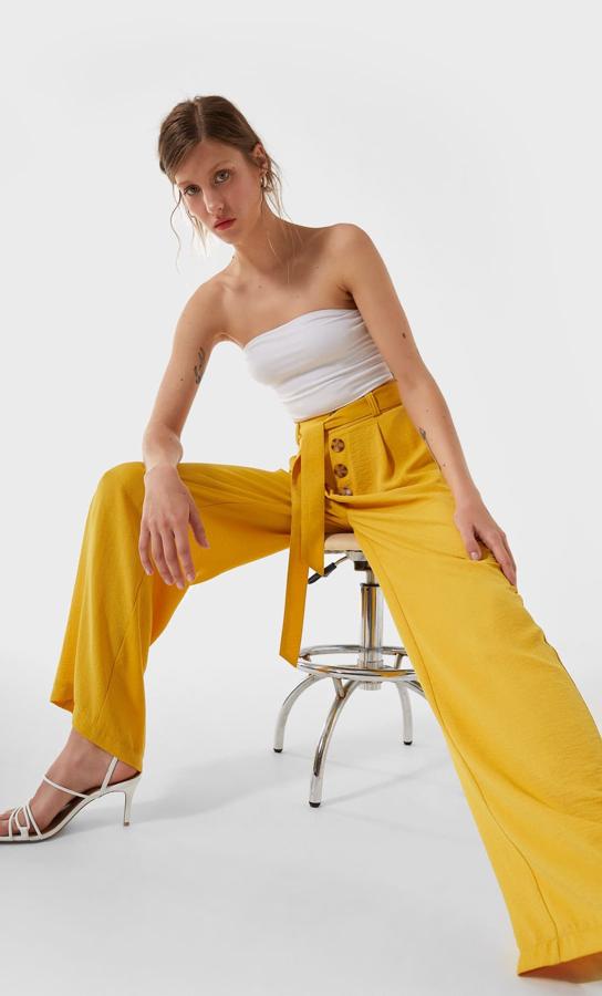 En un vistoso color amarillo, con lazada a tono y botones a contraste en el frontal, este pantalón palazzo costaba 19,99 euros y ahora podemos comprarlo por 12,99 euros en las tallas S y L.