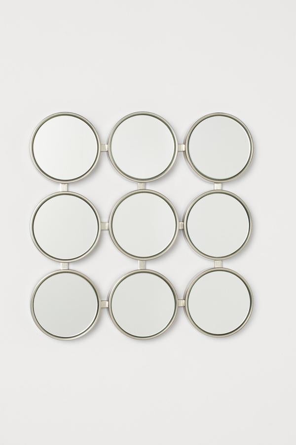 Este espejo con marco de metal formado por nueve espejos redondos en tres hileras, cuenta con anillas de metal en la parte trasera para colgar. Cada espejo tiene un diámetro de 10,5 centímetros, y tiene un precio de 21,99 euros.