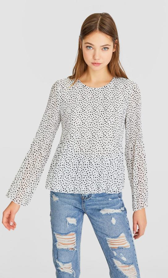 Blanca con motas negras, esta blusa de manga larga y cuello redondo tiene un precio de 7,99 euros (antes 17,99 euros) y todavía podemos encontrarla en la talla M, aunque se está agotando.