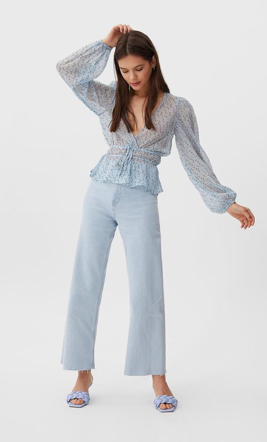 En tejido semitransparente, color azul y estampado blanco y negro, esta blusa de escote de pico cruzado y cintas a tono en la cintura costaba 15,99 euros y ahora podemos comprarla por 7,99 euros en la talla L.