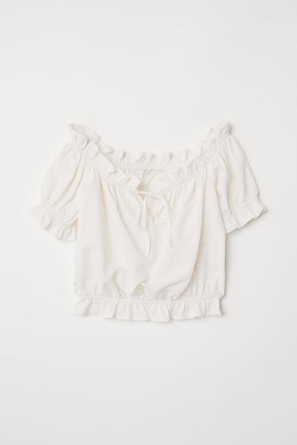 En mezcla de lyocell sostenible, esta blusa de hombros descubiertos de H&M viene con elástico y volante en la parte superior con una pequeña abertura con lazada, mangas cotas y elásticas con ribete de volante, al igual que el bajo. De 29,99 euros ha pasado a 17,99 euros y está disponible entre las tallas 40 y 44.