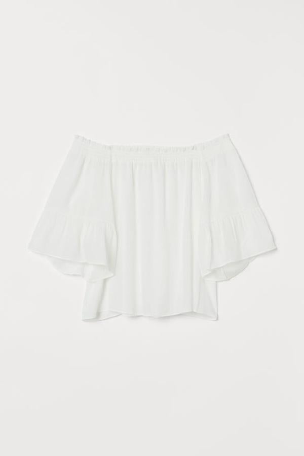 En tejido arrugado, con fruncido con ribete corto de volante en la parte superior y mangas tres cuartos trompeta de diseño ancho, esta blusa de H&M cuesta 19,99 euros y solo queda en las tallas 36 y 38.