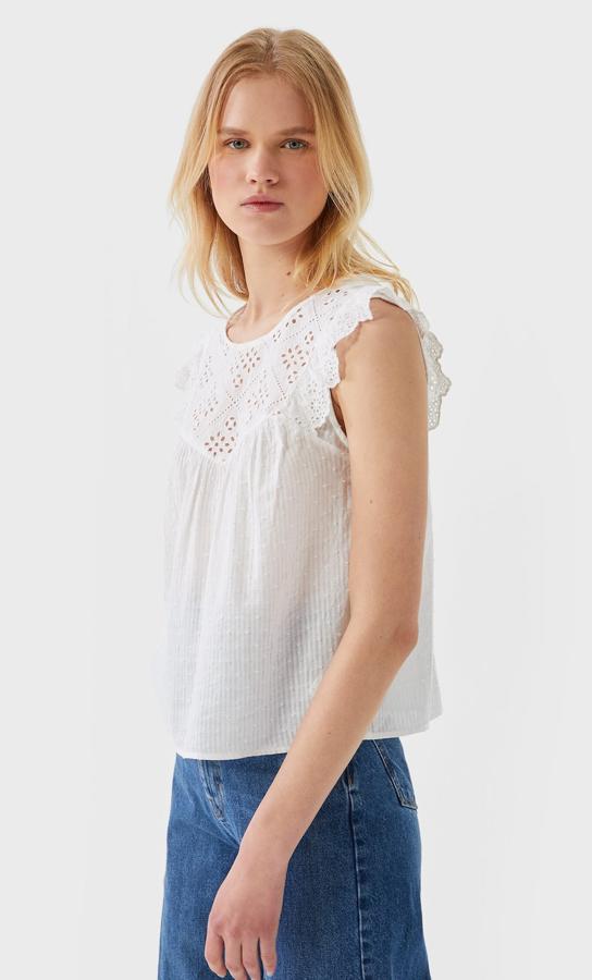 En color crudo, esta blusa con bordado suizo y cuello redondo está confeccionada en 100 % algodón y tiene un precio de 7,99 euros.