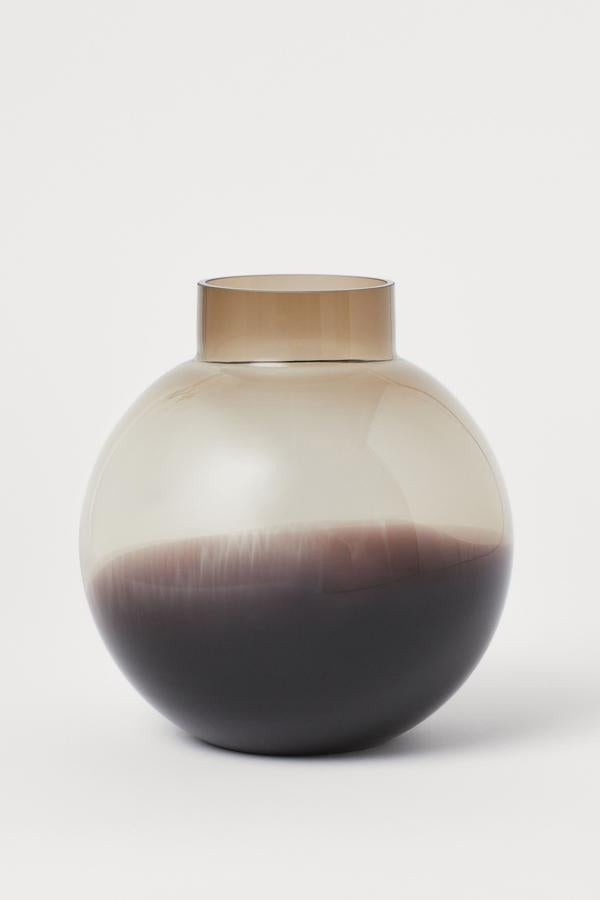 Este jarrón redondo de vidrio con base tonalizada tiene una altura de 21 centímetros, y un diámetro de 20. Tiene un precio de 17,99 euros.