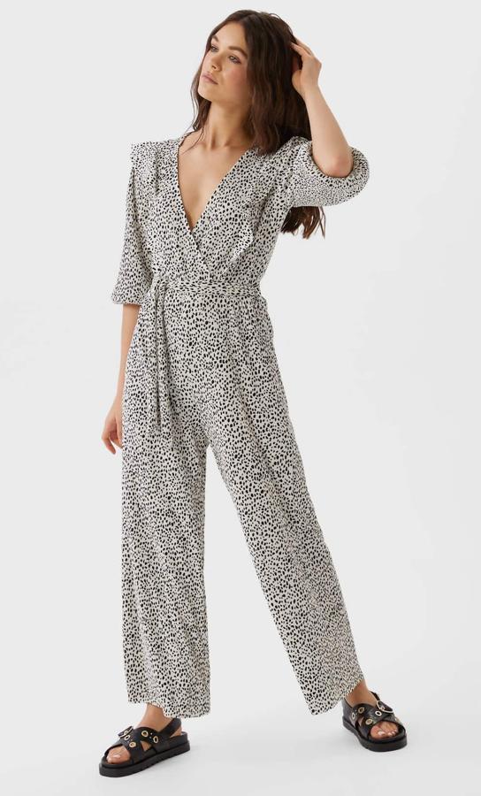 En color crudo con pequeños topos negros, este mono plisado con escote de pico y detalle de volante y lazada en la cintura tiene un precio rebajado de 15,99 euros.