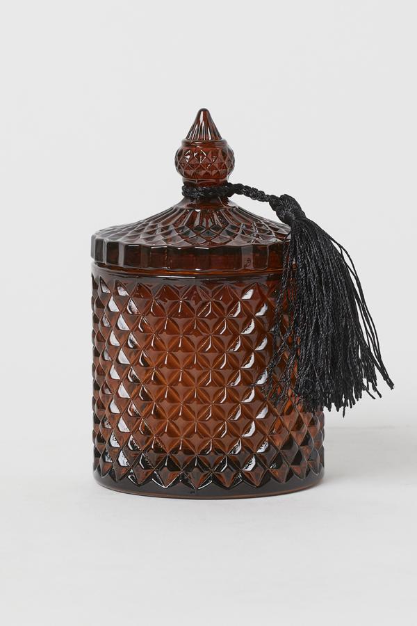 Disponible en color marrón, verde o rosa, esta vela aromática en recipiente con acabado en relieve y tapa con bola extraíble tiene un precio de 14,99 euros.