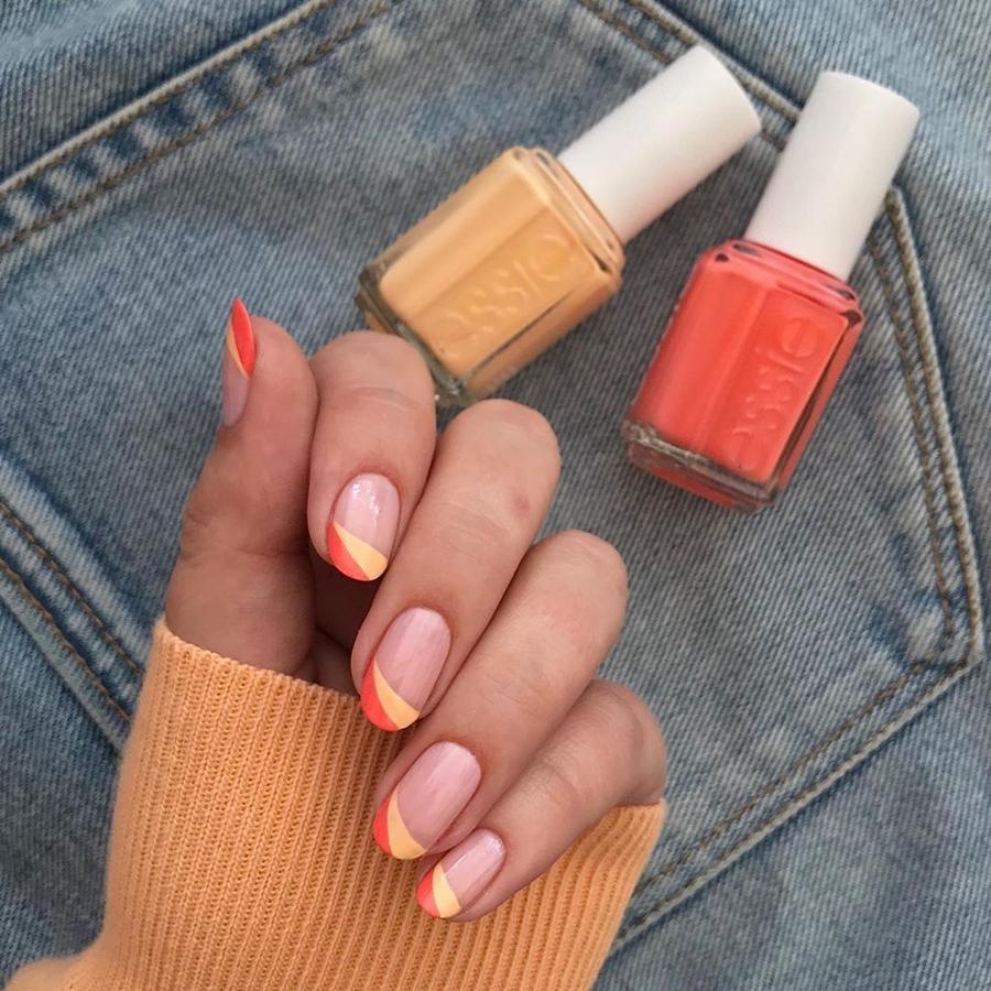 La manicura francesa esta temporada viene en diferentes versiones. Esta en diferentes tonos conun diseño de rayas en naranja y amarillo es ideal.