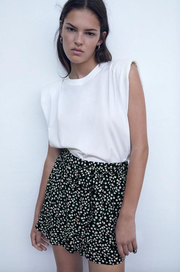 De tiro alto con cintura elástica en la espalda, esta falda bermuda de Zara en color negro con estampado de margaritas viene con detalle de lazo combinado a tono y bajo acabado con volantes. Cuesta 22,95 euros y está disponible entre las tallas XS y XL.