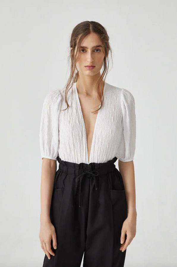 De manga larga con detalle de volumen, este body en color blanco con escote en forma de pico y confeccionado en tejido ligeramente elástico es de Pull&Bear. Solo lo encontramos en la web por 19,99 euros en las tallas S, M y L.