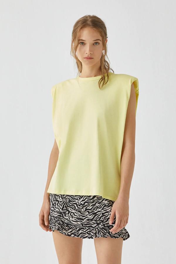 Esta camiseta de manga sisa en color amarillo está disponible en varios colores. Con detalle de hombreras y cuello redondo, está confeccionada en algodón y tiene un precio de 15,99 euros.