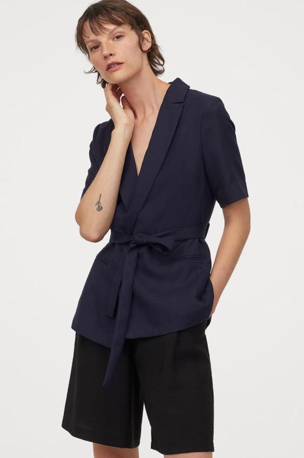 En azul marino y con cinturón de anudar extraíble a tono, esta blazer de manga corta que solo se vende en la web de H&M es entallada y tiene solapas de muesca, mangas cortas sin forrar y bolsillos ribeteados delante. Tiene un precio de 39,99 euros y está disponible entre las tallas 32 y 50.