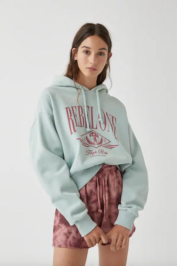 En Pull&Bear hemos encontrado esta sudadera en verde menta con ilustración y texto en contraste y color rojizo con manga larga y capucha ajustable con cordón. Cuesta 19,99 euros, solo la venden en la web y está disponible entre las tallas XS y XL.