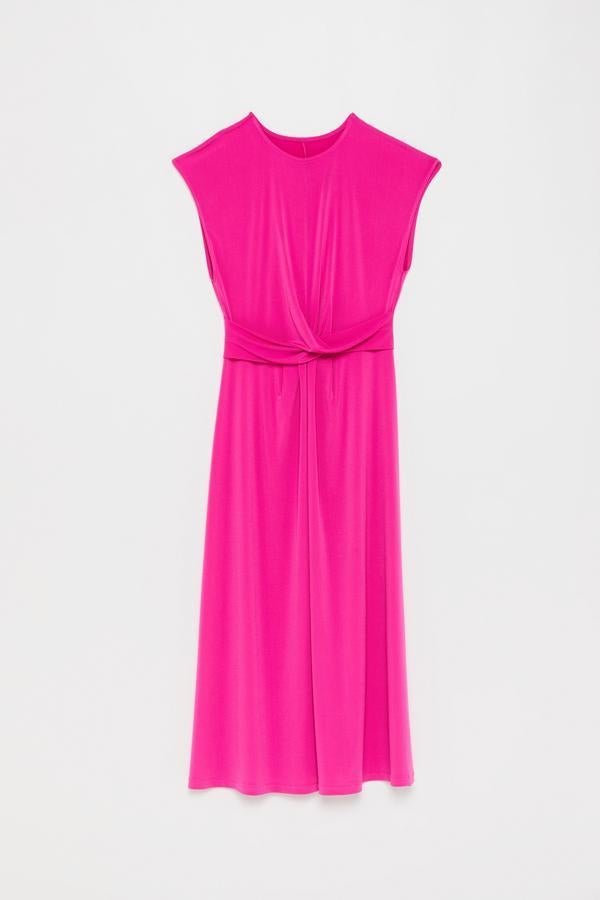 En fucsia, con el cuello redondo, falda plisada y nudo delantero a la altura de la cintura. Este vestido es de Sfera y ahora solo cuesta 19.99 euros.