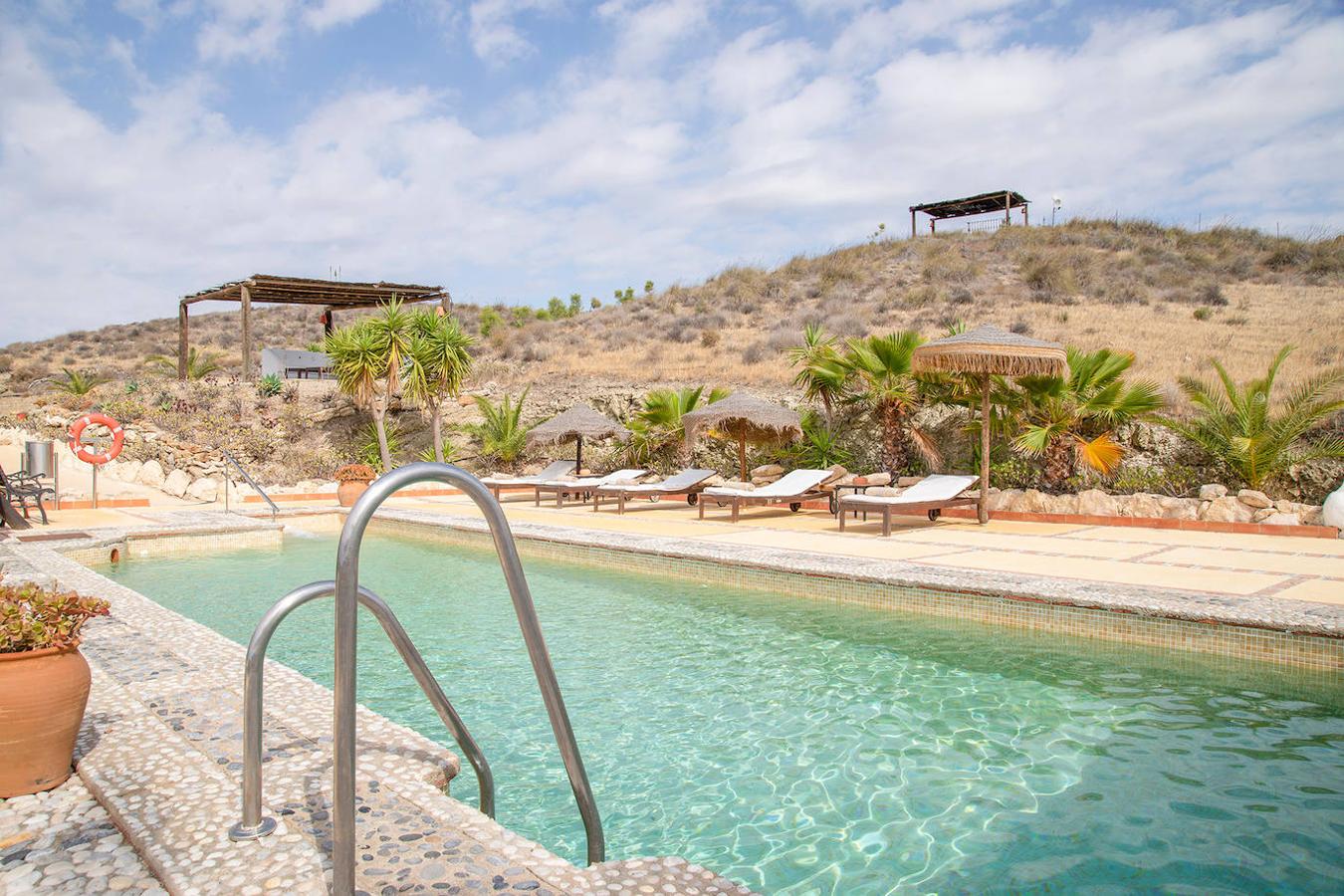 Un oasis de paz en el corazón Cabo de Gata (Almería). El paisaje desértico y espectacular de Agua Amarga arropa esta casa rural para 30 personas con piscina, patios, chillouts, muros encalados, jardines con cactus... Para una estancia inolvidable.