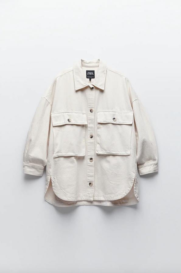 Con bajo asimétrico y bolsillos de plastrón con solapa en el frontal, esta sobrecamisa de Zara en color crudo viene con cuello solapa y manga larga. Tiene un precio de 35,95 euros y está disponible entre las tallas XS y XL.