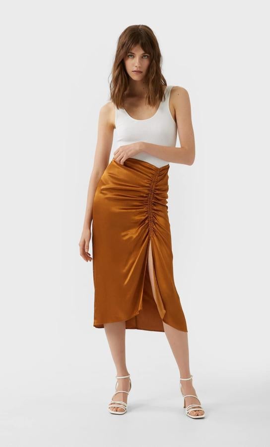 Diseño midi con frunce y abertura en el lateral para esta bonita falda de Stradivarius en camel oscuro. Cuesta 19,99 euros y está disponible entre las tallas XS y XL.