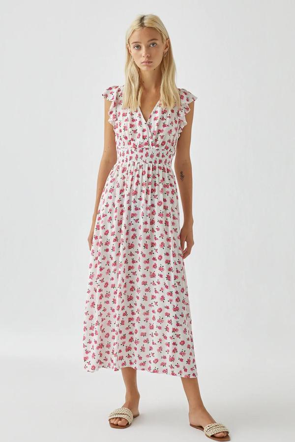 En color blanco con flores en rosa, este vestido con goma en la cintura es de Pull & Bear y cuenta con manga corta con detalle de volante. Tiene un precio de 25,99 euros.