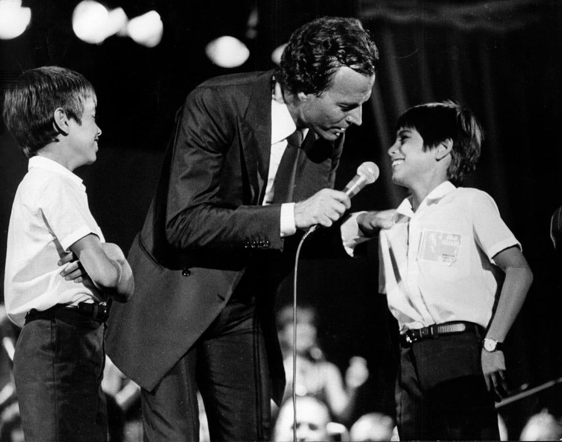 Julio Iglesias sobre el escenario junto a sus hijos Enrique y Julio José (1973) en una foto tomada durante un concierto en la década de los años 80.