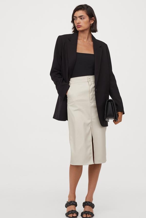 En piel sintética y color beige claro, esta falda midi de H&M viene con bolsillos diagonales y abertura delantera. Con botones de presión revestidos y cierre de cremallera, cuesta 29,99 euros y está disponible entre las tallas 32 y 50 únicamente en la página web de la firma.
