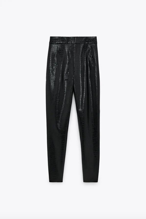 En Zara hemos encontrado este pantalón de tiro alto en efecto piel de cocodrilo con cierre lateral con cremallera oculta en la costura. En color negro, cuesta 25,95 euros y está disponible entre las tallas XS y XXL.