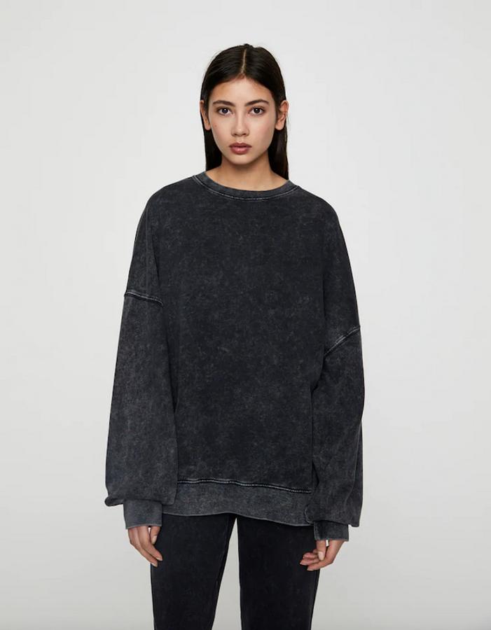 De color negro con efecto lavado, mangas largas y cuello redondo, esta sudadera de diseño oversize con hombros caídos tenía un precio de 17,99 euros y ahora podemos encontrarla por 5,99 euros en las tallas XS y L.