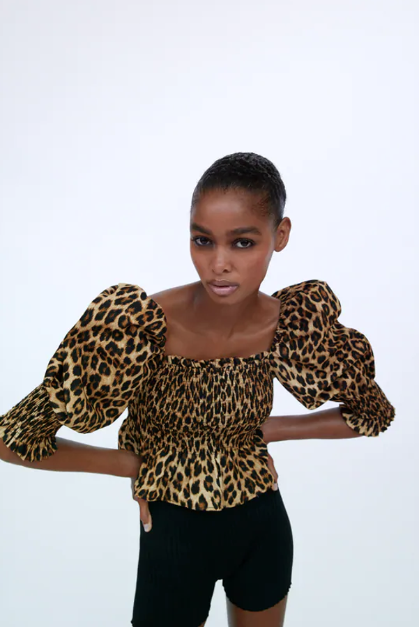 Cuerpo con escote recto y manga abullonada por debajo del codo, con decoraciones de elásticos tipo nido de abeja y bajo acabado con volante (Zara, 25,95 euros).