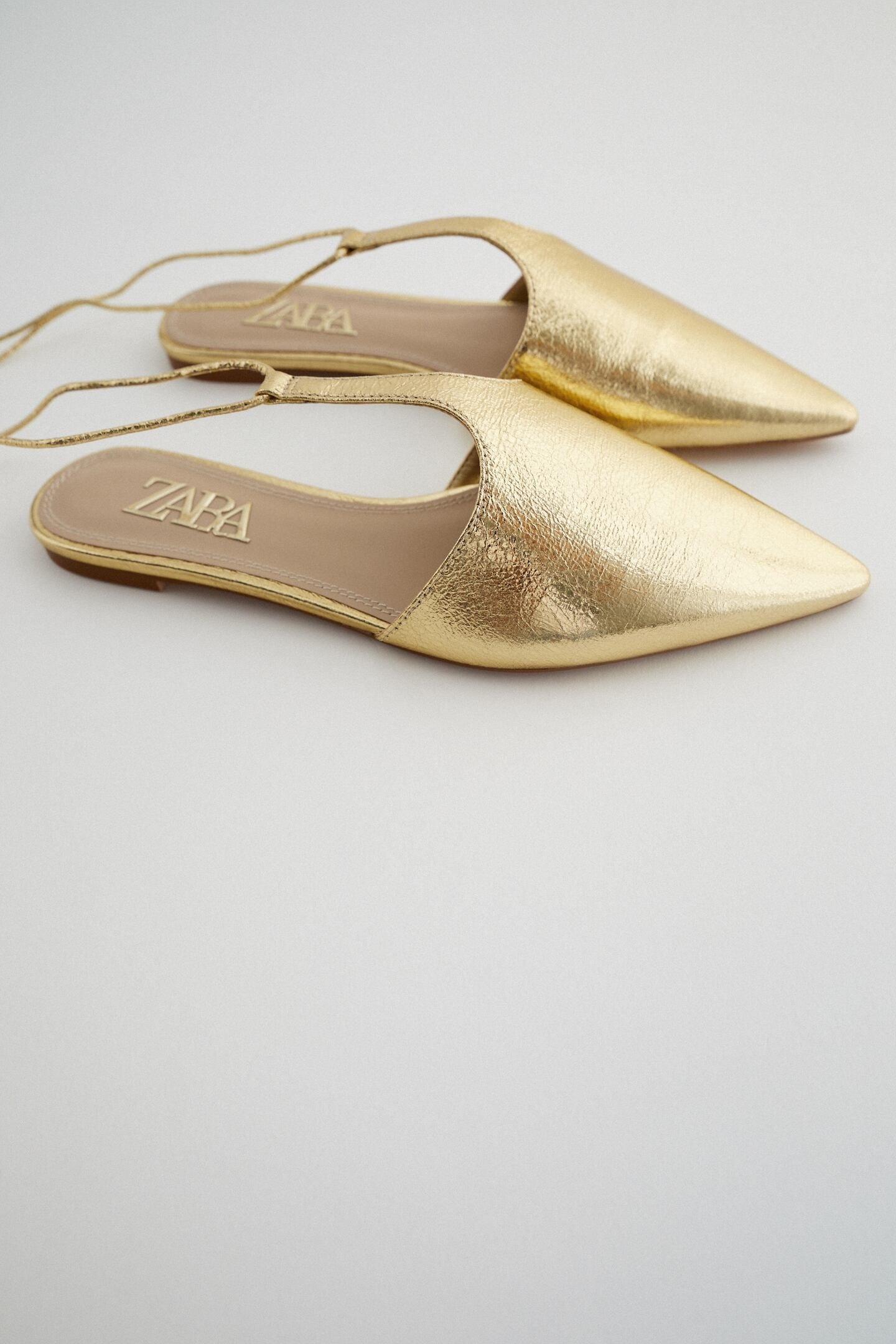 Entre las novedades de Zara también hemos encontrado un nuevo concepto para llevar los mules: en forma de T sobre el empeine, atados y del color más glamuroso: el dorado. (29,95 euros).