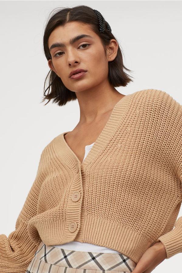 Diseño corto en color beige para este cárdigan de H&M en punto suave de mezcla de algodón con escote de pico pronunciado, botones delanteros grandes y mangas amplias con puños ceñidos en canalé. Cuesta 19,99 euros y está disponible entre las tallas XS y XL.