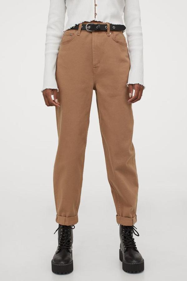 Confeccionado en sarga con diseño tobillero mom fit loose, este pantalón de H&M en marrón medio tiene corte holgado y talle alto, con perneras ajustadas en los bajos recogidos. Cuesta 14,99 euros y en la web únicamente está disponible en la talla 44.
