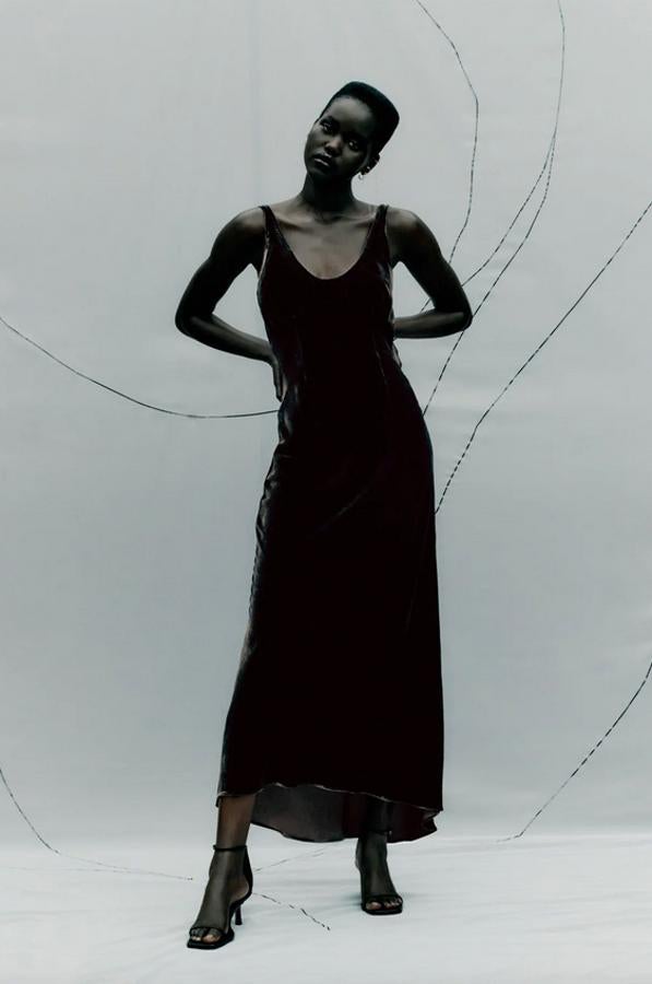 En color marrón oscuro, con escote de pico y tirantes anchos, este vestido lencero de terciopelo de Zara viene con bajo asimétrico y cierre de botones forrados en la espalda y cuesta 79,95 euros. Podemos encontrarlo en las tallas XS, S y M.