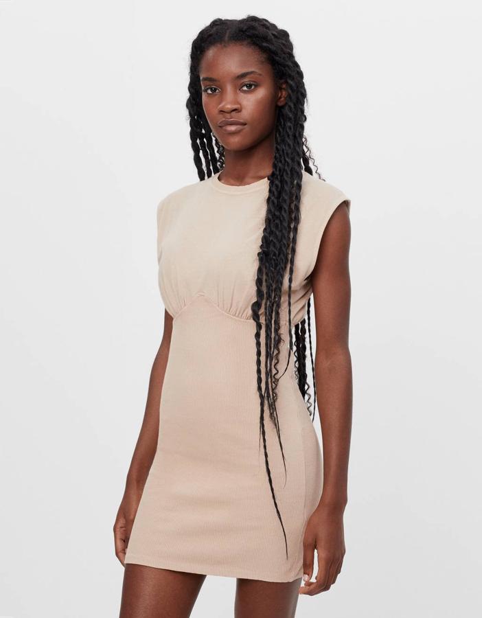 Con diseño corset en la parte superior, este vestido corto ajustado en rosa palo es de Bershka. Viene sin mangas, costaba 15,99 euros y está disponible por 9,95 euros entre las tallas XS y L, y en color negro.