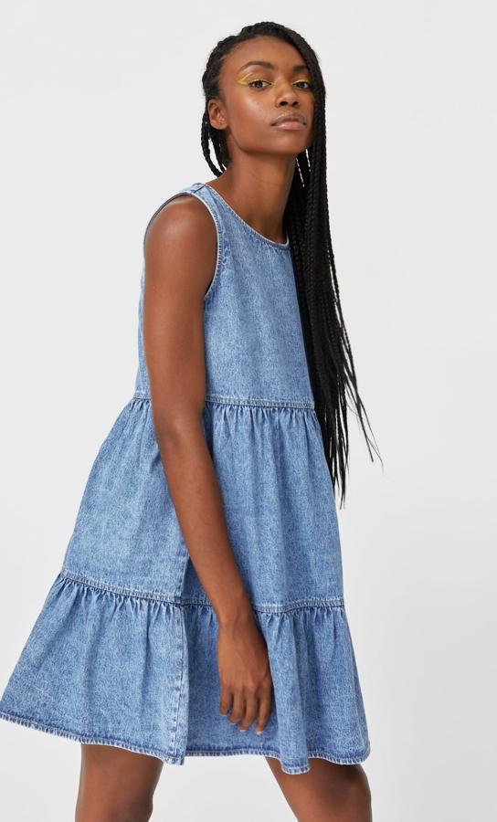 Este vestido corto en color azul denim con cuello redondo y manga sisa cuenta con bajo acabado en volante y tiene un precio de 18,19 euros.