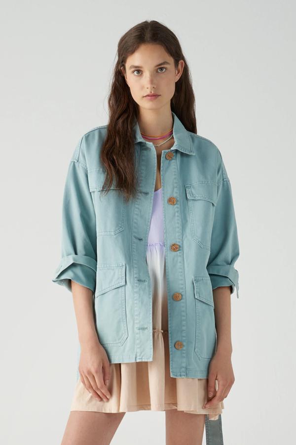 Esta chaqueta estilo worker en color azul claro cuenta con cinturón y bolsillos delanteros. Con cierre de botones, está confeccionada en 100% algodón y tiene un precio de 19,99 euros. Es de Pull & Bear.