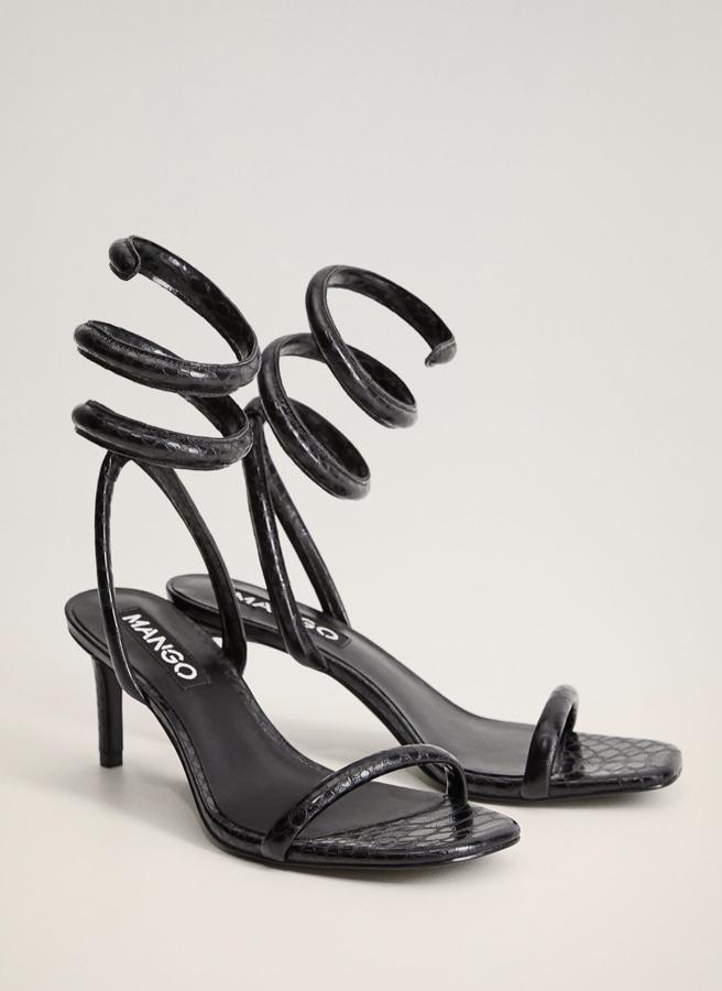 En color negro y con efecto de serpiente, esta sandalia de Mango con punta cuadrada y diseño de tiras cuenta con un tacón de 7 centímetros y tiene un precio de 39,99 euros.
