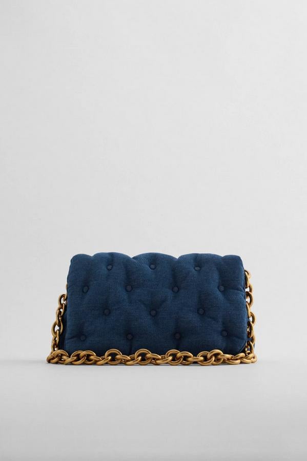 Formato maxi bandolera en azul vaquero para este bolso de Zara con cuerpo y solapa acolchados con detalle de hombros forrados. Con asa de hombro con cadena gruesa en dorado, cuesta 29,95 euros.
