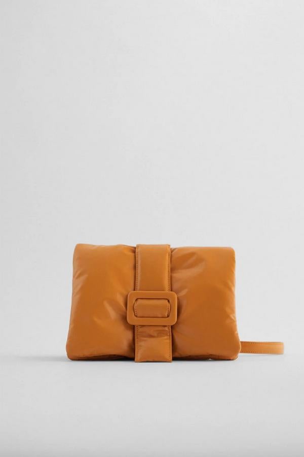 Disponible en negro o en naranja, este bolso formato bandolera de Zara viene con cuerpo acolchado con detalle de hebilla a tono y asa de hombro en cadena con combinación de materiales. Con cierre mediante imán, cuesta 25,95 euros.
