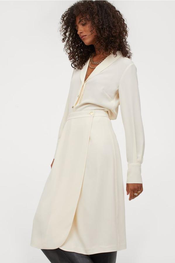 Con caída elegante, esta falda midi cruzada de talle alto con pliegues en la cintura, botón dorado en el frontal y parte delantera redondeada cuesta 34,99 euros y está disponible en la talla 38 y entre la 42 y la 50.