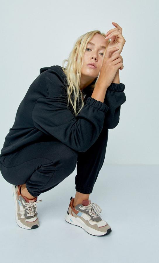 Hace años que no veíamos por la calle un chándal de felpa. ¡Y vuelven¡ ¿Quieres ser de las primeras en volver a llevarlo? Este modelo de sudadera con capucha en color negro es de Stradivarius y tiene un precio de 17,99 la parte de arriba y 12,99 la de abajo.