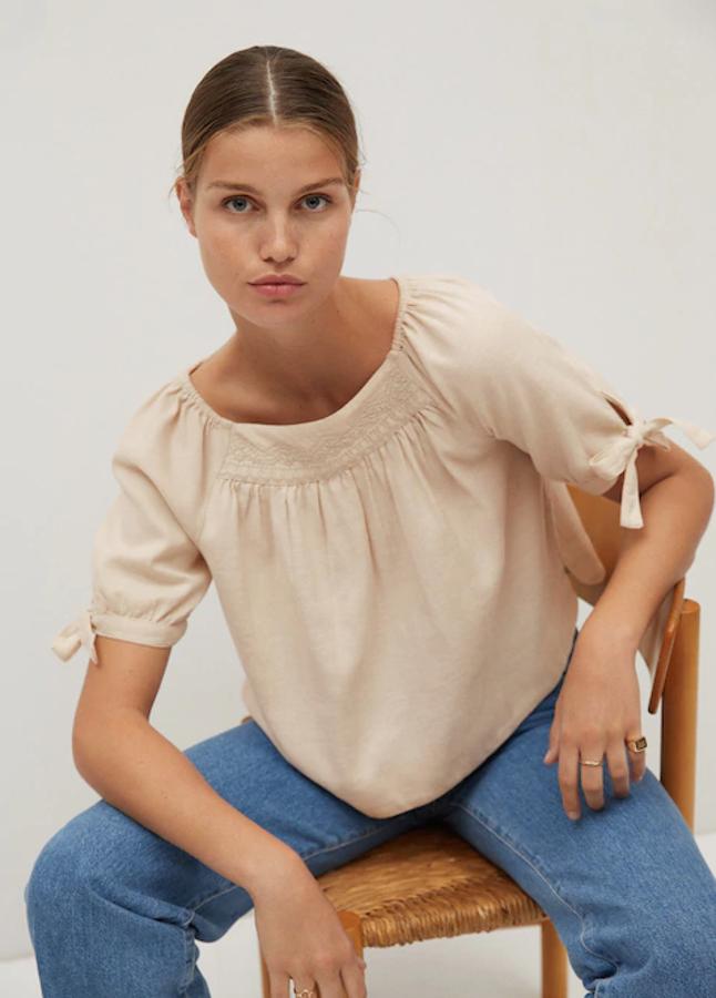 Diseño ancho y cuello redondo para esta blusa de algodón de Mango con detalles elásticos en las mangas cortas con cierre de lazo y dibujo tejido en el frontal. Cuesta 25,99 euros y está disponible entre las tallas XS y L.
