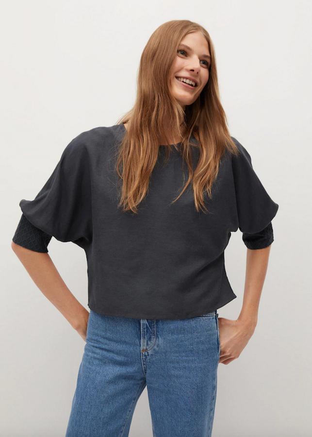 En tejido fluido, con diseño crop ancho y cuello redondo, esta blusa de Mango con puños bordados y mangas tres cuartos de murciélago cuesta 25,99 euros y podemos encontrarla en gris antracita entre las tallas XS y L.