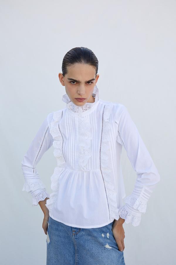 Blusa blanca con pechera con volantes calados y cuello subido, de Sfera (19,99 euros).